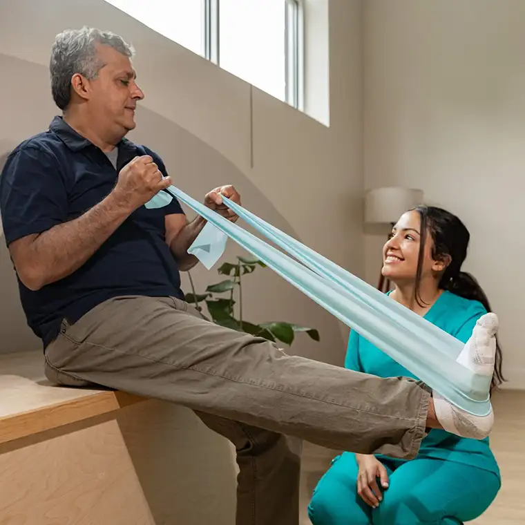 Qualified Physiotherapist assisting a client to regain mobility with resistance band exercises